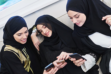 Image showing Portrait of Arabian girls wearing modern abaya using mobile phone