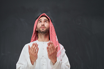 Image showing Arab man in traditional clothes praying to God or making dua