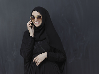 Image showing Young muslim businesswoman in traditional clothes or abaya using smartphone