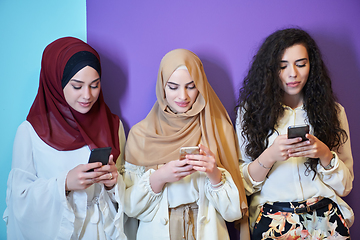 Image showing Muslim women using mobile phones isolated on blue and purple background