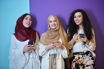 Image showing Muslim women using mobile phones isolated on blue and purple background