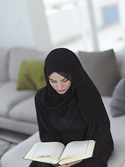 Image showing Portrait of young muslim woman reading Quran in modern home