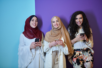 Image showing Muslim women using mobile phones isolated on blue and purple background