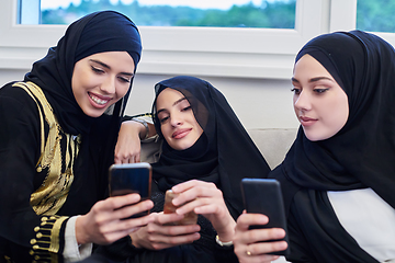 Image showing Portrait of Arabian girls wearing modern abaya using mobile phone