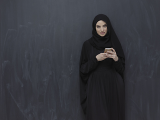 Image showing Young muslim businesswoman in traditional clothes or abaya using smartphone
