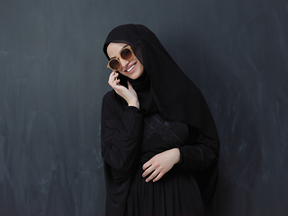 Image showing Young muslim businesswoman in traditional clothes or abaya using smartphone