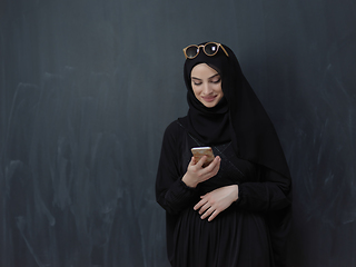 Image showing Young muslim businesswoman in traditional clothes or abaya using smartphone