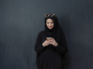 Image showing Young muslim businesswoman in traditional clothes or abaya using smartphone