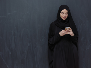 Image showing Young muslim businesswoman in traditional clothes or abaya using smartphone