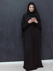 Image showing Young muslim businesswoman in traditional clothes or abaya using smartphone