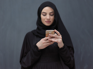 Image showing Young muslim businesswoman in traditional clothes or abaya using smartphone