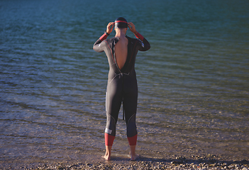 Image showing authentic triathlon athlete getting ready for swimming training on lake