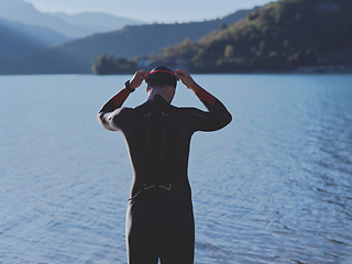 Image showing authentic triathlon athlete getting ready for swimming training on lake