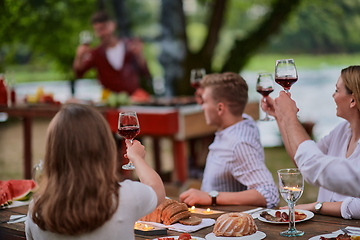 Image showing friends toasting red wine glass while having picnic french dinner party outdoor