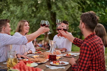 Image showing friends toasting red wine glass while having picnic french dinner party outdoor