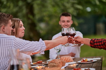 Image showing friends toasting red wine glass while having picnic french dinner party outdoor