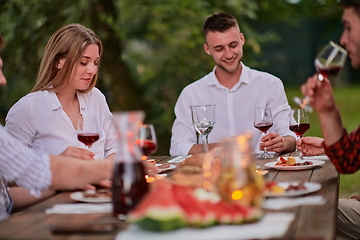 Image showing friends toasting red wine glass while having picnic french dinner party outdoor