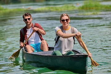 Image showing friends are canoeing in a wild river