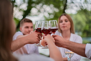 Image showing friends toasting red wine glass while having picnic french dinner party outdoor