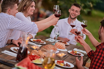 Image showing friends toasting red wine glass while having picnic french dinner party outdoor