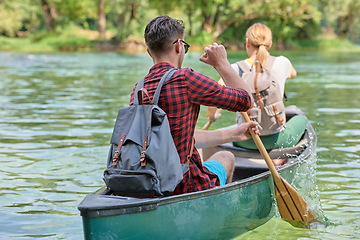 Image showing friends are canoeing in a wild river