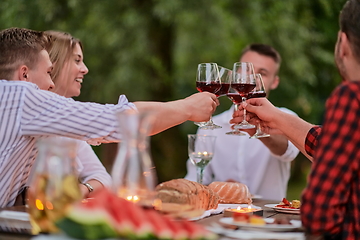 Image showing friends toasting red wine glass while having picnic french dinner party outdoor