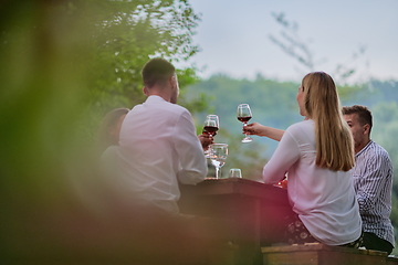 Image showing friends toasting red wine glass while having picnic french dinner party outdoor