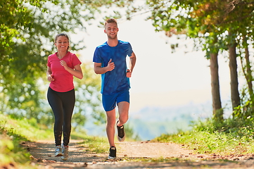 Image showing couple enjoying in a healthy lifestyle while jogging on a country road