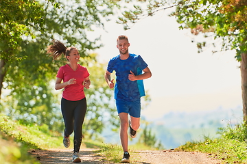 Image showing couple enjoying in a healthy lifestyle while jogging on a country road