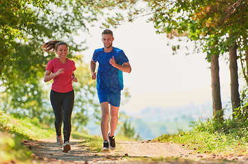 Image showing couple enjoying in a healthy lifestyle while jogging on a country road