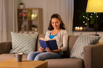 Image showing young woman reading book at home in evening