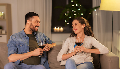 Image showing happy couple drinking red wine at home in evening