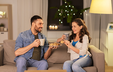 Image showing happy couple drinking tea with cookies at home