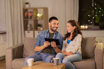 Image showing happy couple using tablet pc at home in evening