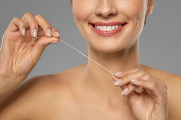 Image showing smiling woman with dental floss cleaning teeth