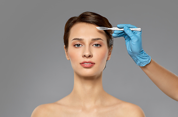 Image showing beautiful young woman and hand with scalpel