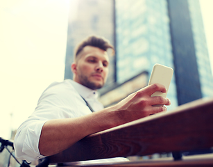 Image showing close up of man texting on smartphone in city