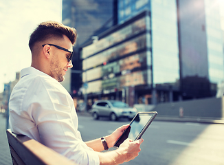 Image showing man with tablet pc sitting on city street bench