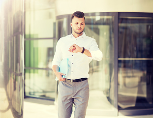 Image showing man with folder looking at wristwatch on street