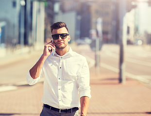 Image showing happy man with smartphone calling on city street