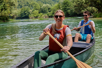 Image showing friends are canoeing in a wild river