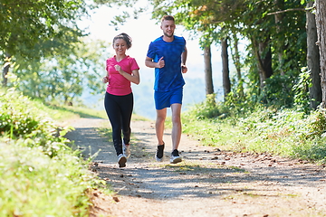 Image showing couple enjoying in a healthy lifestyle while jogging on a country road