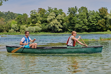 Image showing friends are canoeing in a wild river