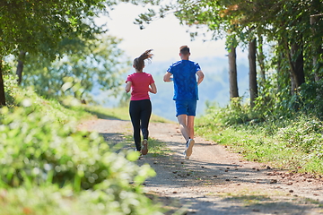 Image showing couple enjoying in a healthy lifestyle while jogging on a country road