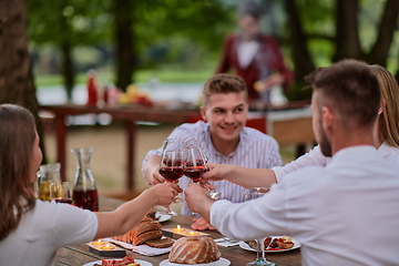 Image showing friends toasting red wine glass while having picnic french dinner party outdoor