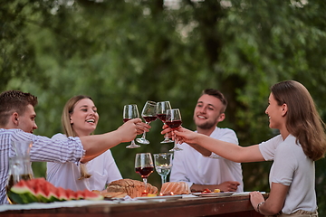 Image showing friends toasting red wine glass while having picnic french dinner party outdoor