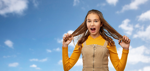 Image showing scared young teenage girl holding her hair strands