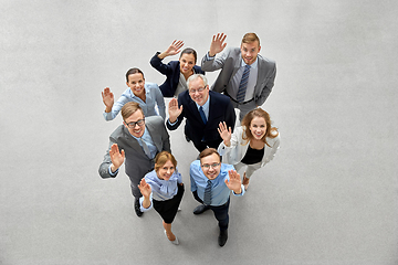 Image showing happy smiling business people waving hands