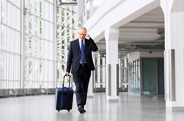 Image showing worried senior businessman walking with travel bag