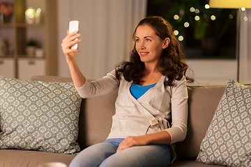 Image showing happy woman taking selfie with smartphone at home